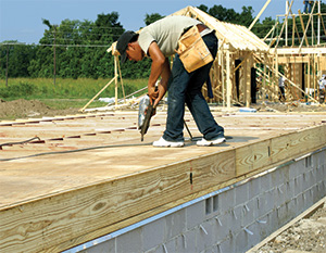 Worker fastening plywood to raised floor 